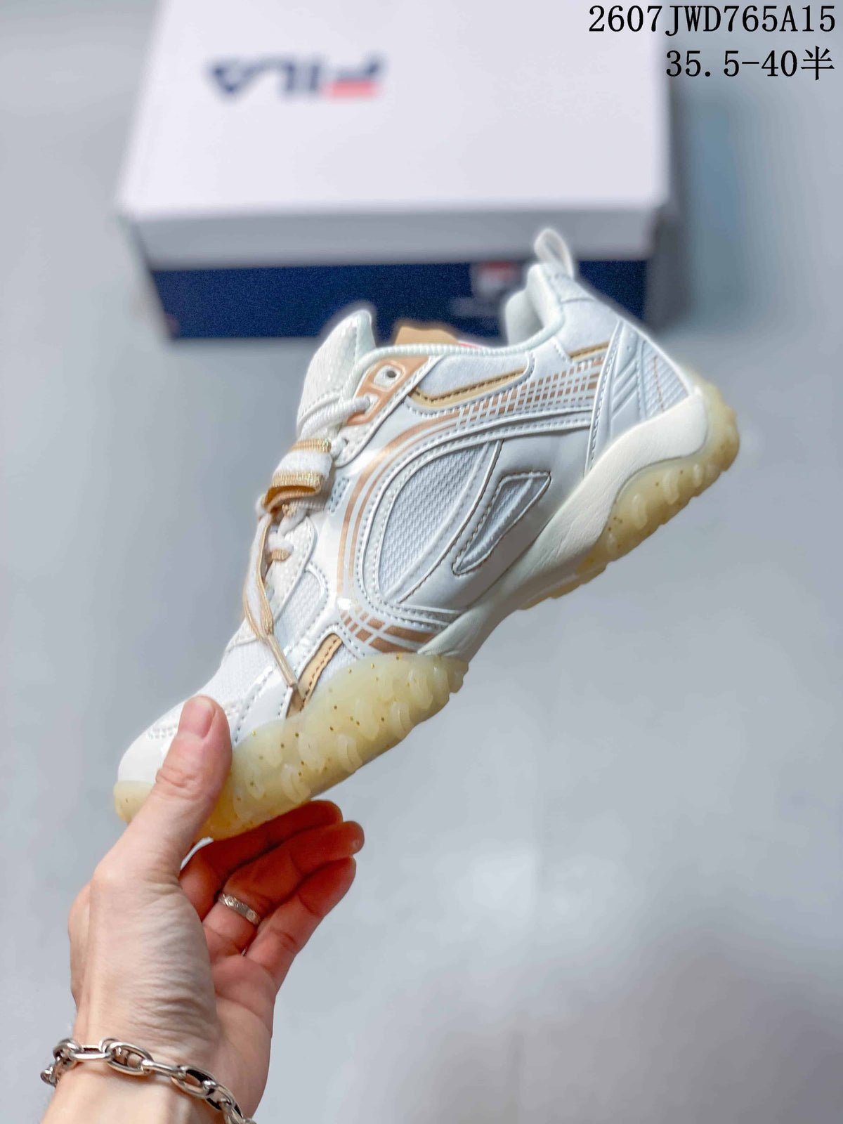 Side profile of the white and gold FILA sneaker showing layered panels, lace detail, and translucent outsole.