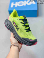 Angled side view of the HOKA running shoe showing the green upper, black midsole, and pink outsole.