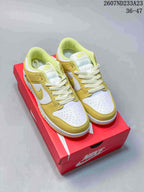 Pair of white and yellow-gold low-top sneakers displayed on a red shoebox.