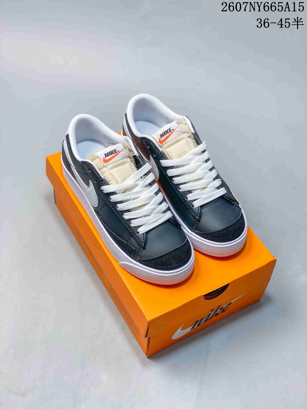 Pair of black and white Nike low-top sneakers displayed on an orange shoebox.