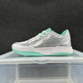 Side view of a silver Nike sneaker with mint-green accents, white laces, a white midsole and green outsole.