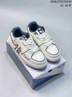 Pair of white and navy MLB low-top sneakers with chunky soles, shown on a shoebox.