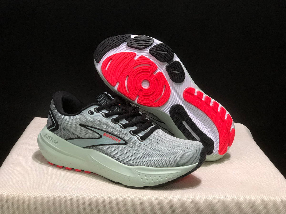 Angled view showing one sneaker's outsole with black and red traction sections and the sculpted midsole.