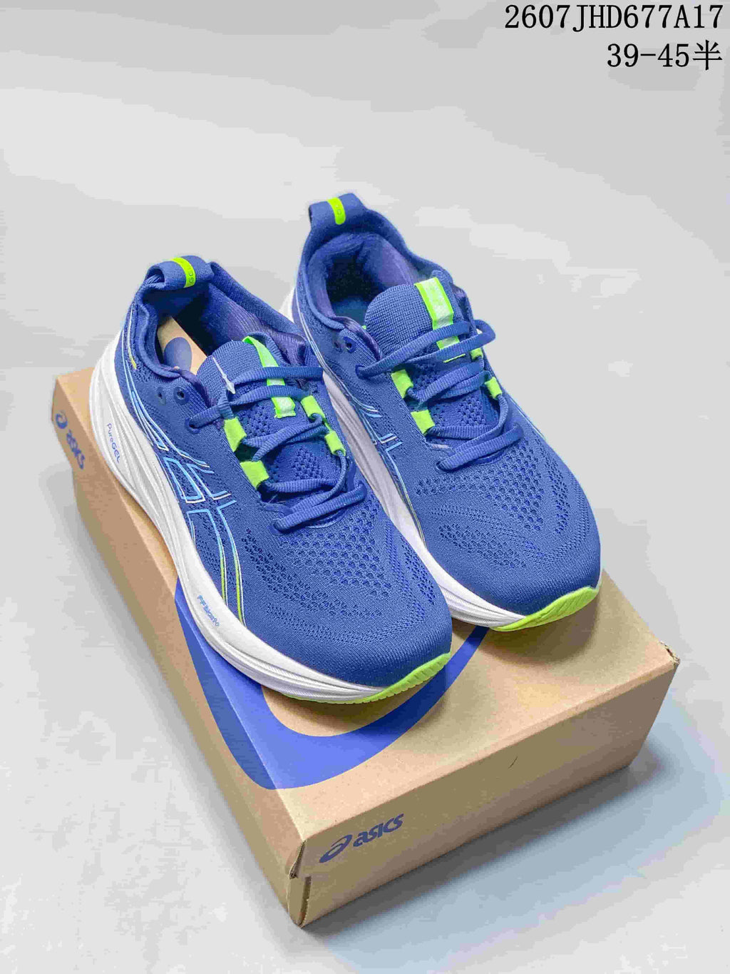 Pair of blue and green ASICS Gel-Nimbus 26 running shoes displayed on an ASICS shoebox.