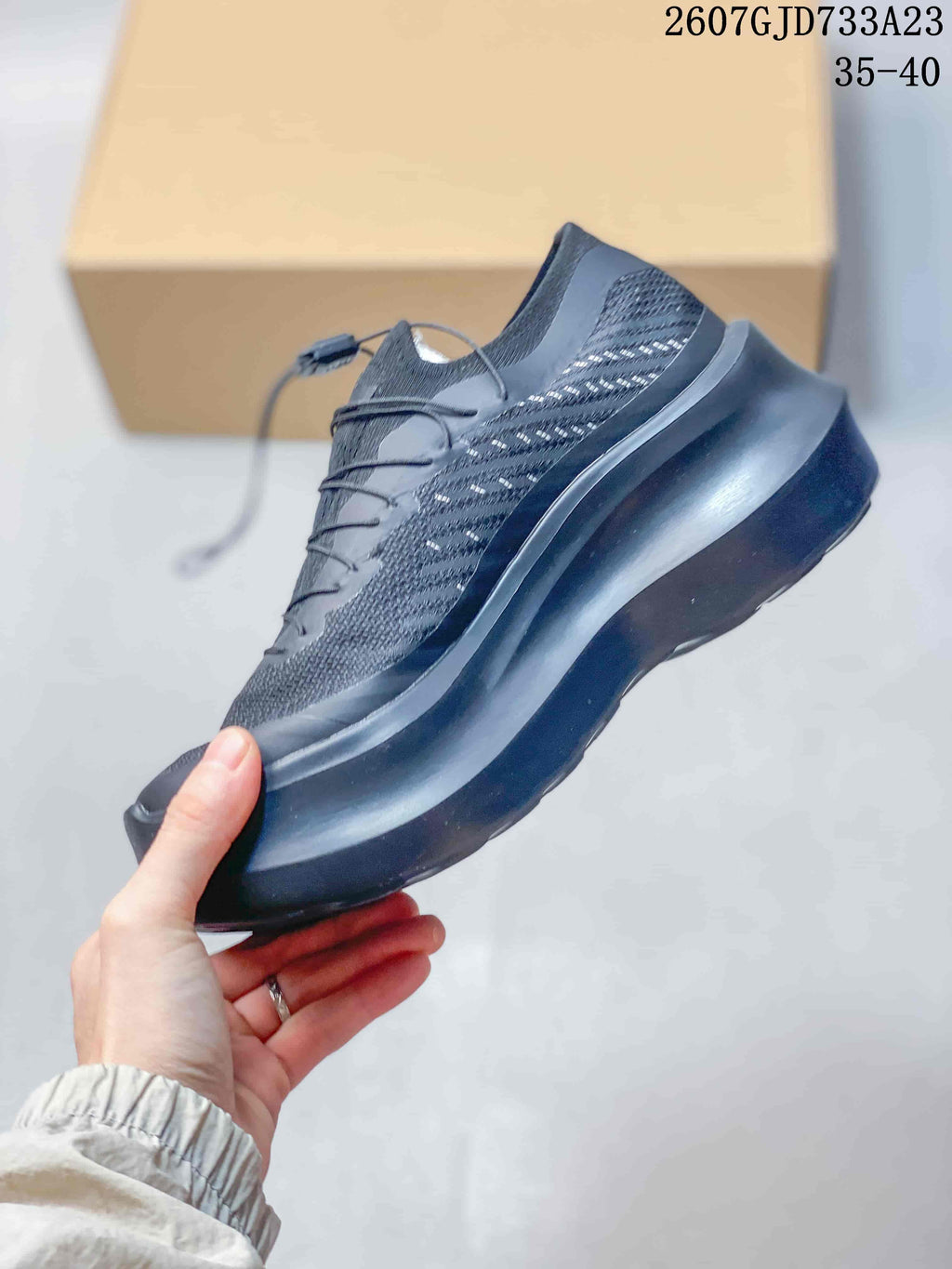 Side profile of the black sneaker showing the textile-style upper, layered overlays, and platform sole.