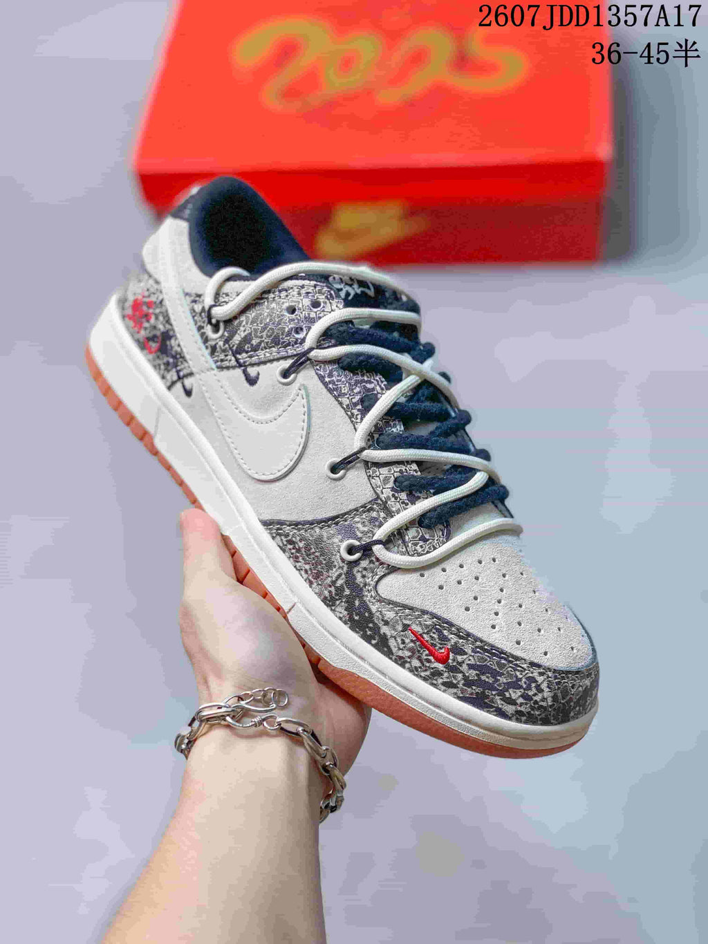 White and grey low-top sneaker with dark patterned overlays, contrasting laces and a gum-colored outsole.