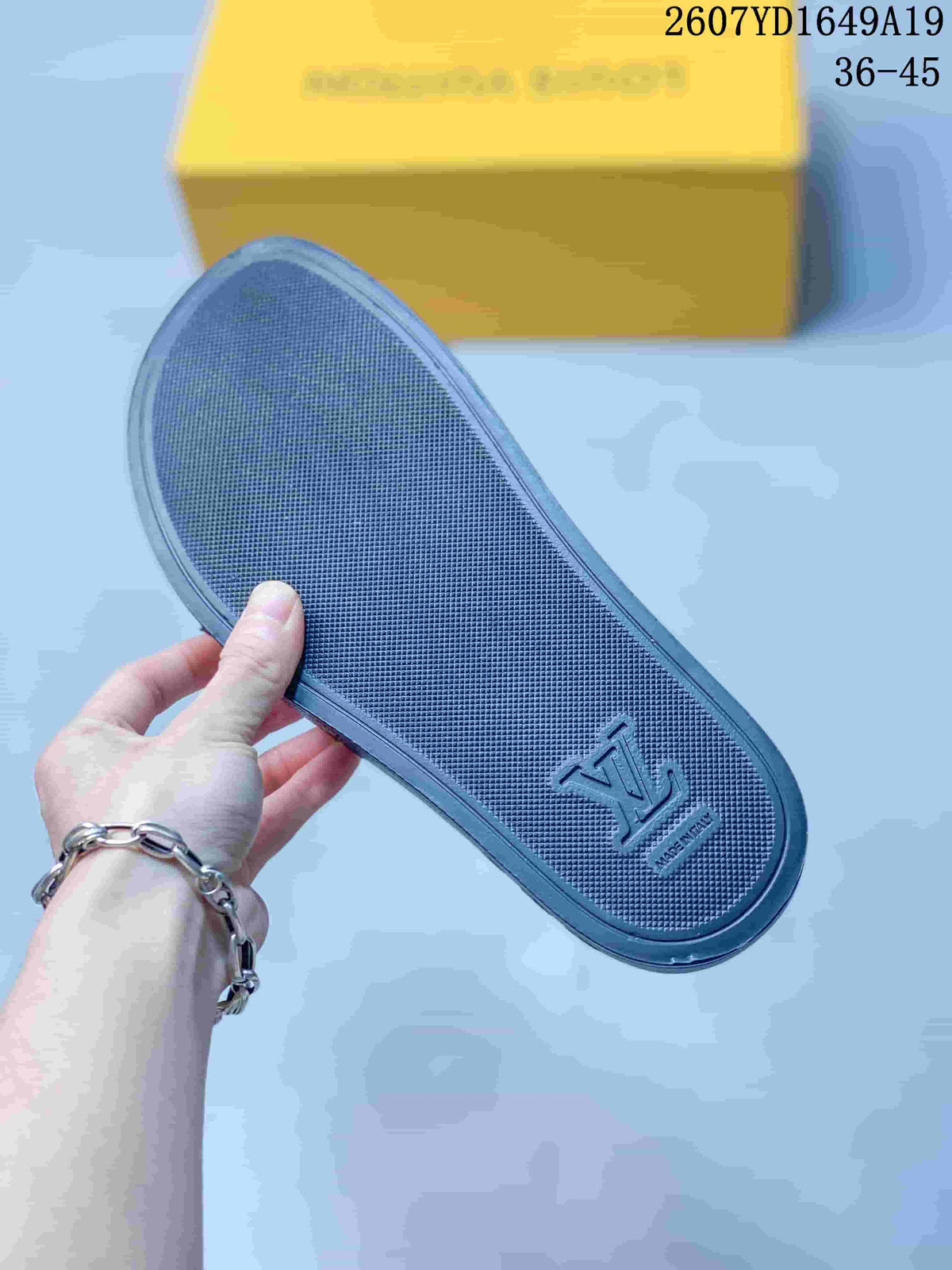 Close-up of the textured black footbed with embossed branding and a yellow box in the background.