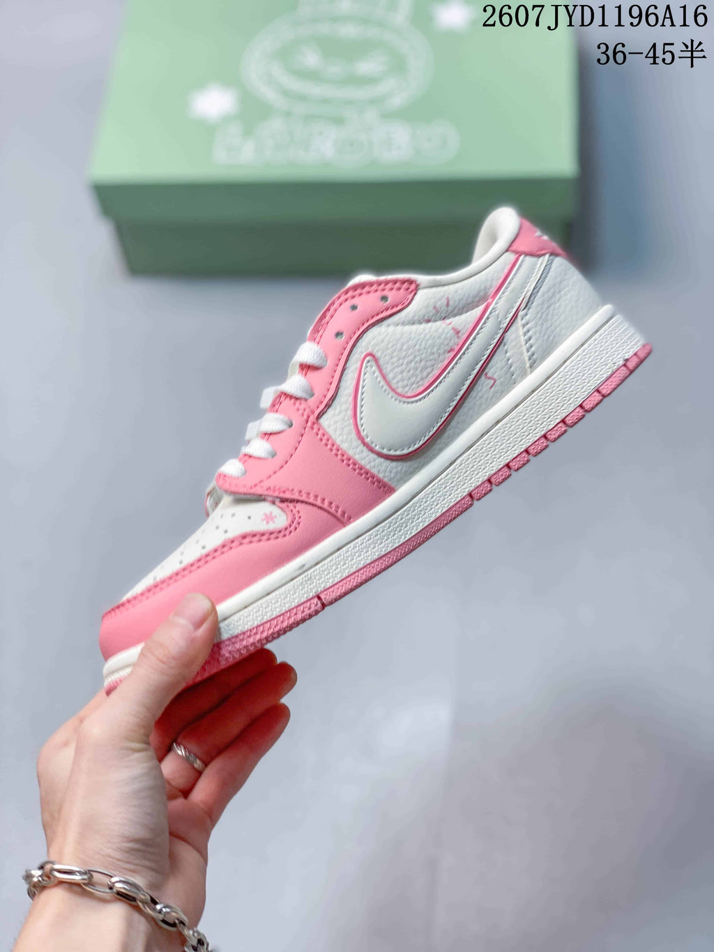 Side profile of the pink and white low-top sneaker showing the Swoosh-style side logo, layered overlays, and textured outsole.