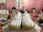 Front view of white Nike basketball sneakers with blue tongue branding, perforated toe boxes, and gum-colored outsoles.