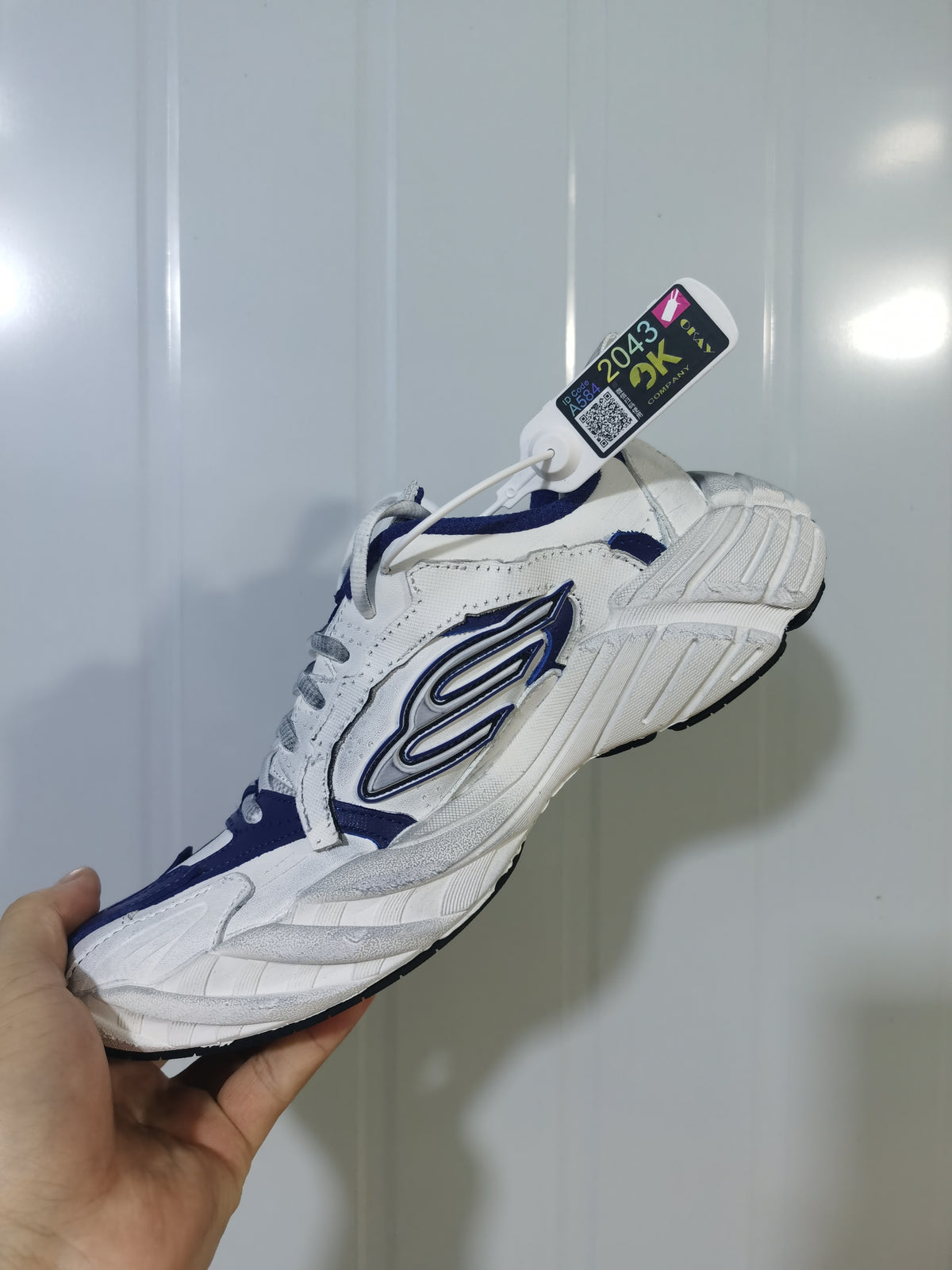Navy and white low-top sneaker shown from the outer side, with layered panels, a contrasting side emblem, and a textured sole.
