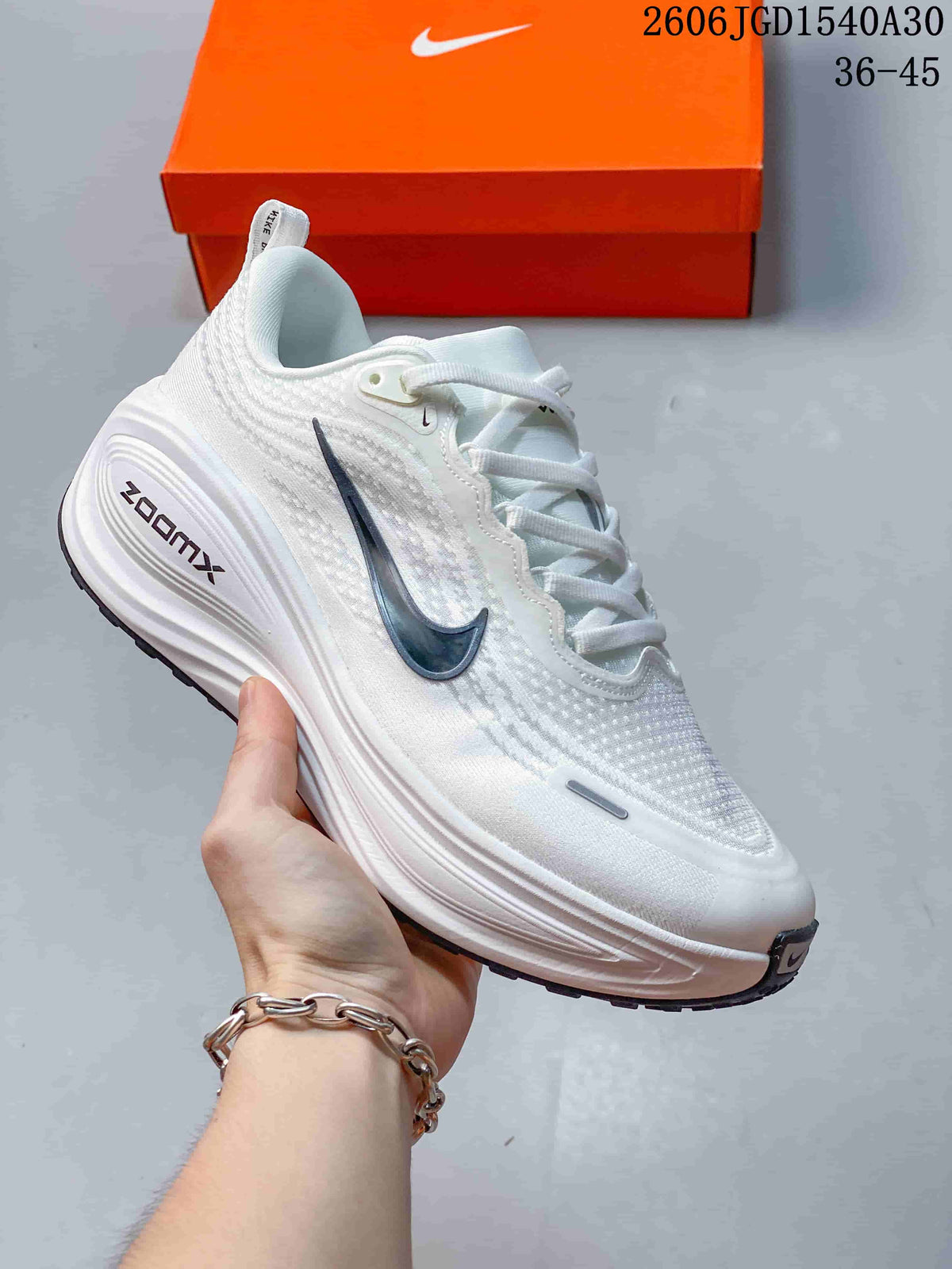 White Nike Vomero Plus running shoe with a dark Swoosh and matching pale sole.