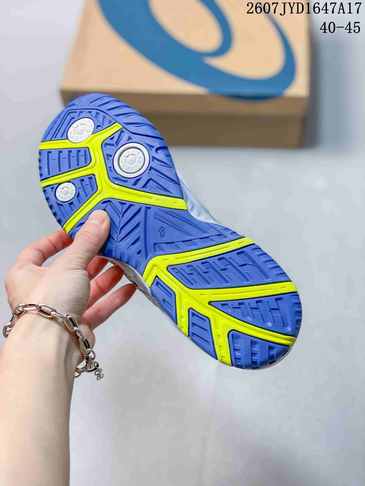 Close-up of the blue outsole with neon yellow sections and circular pivot details; an ASICS shoe box is visible in the background.