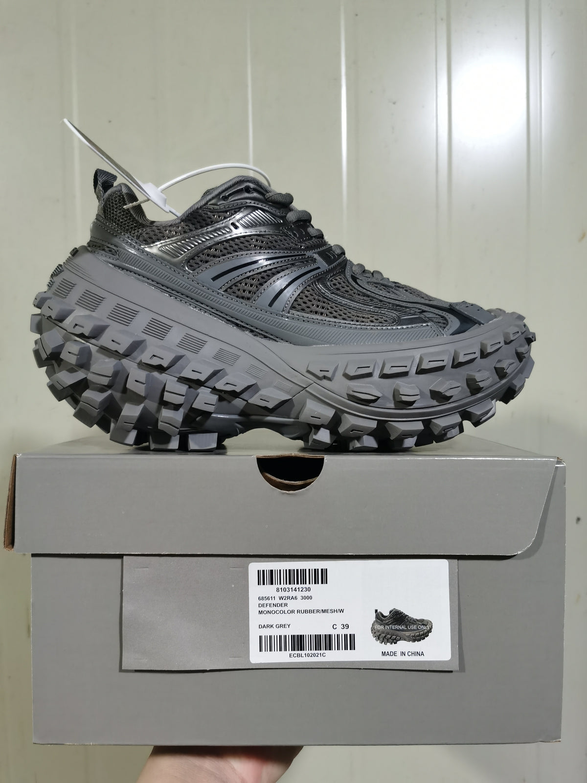 Dark gray Defender sneaker displayed on its box, showing the layered upper, chunky lugged outsole, and box label marked C 39.