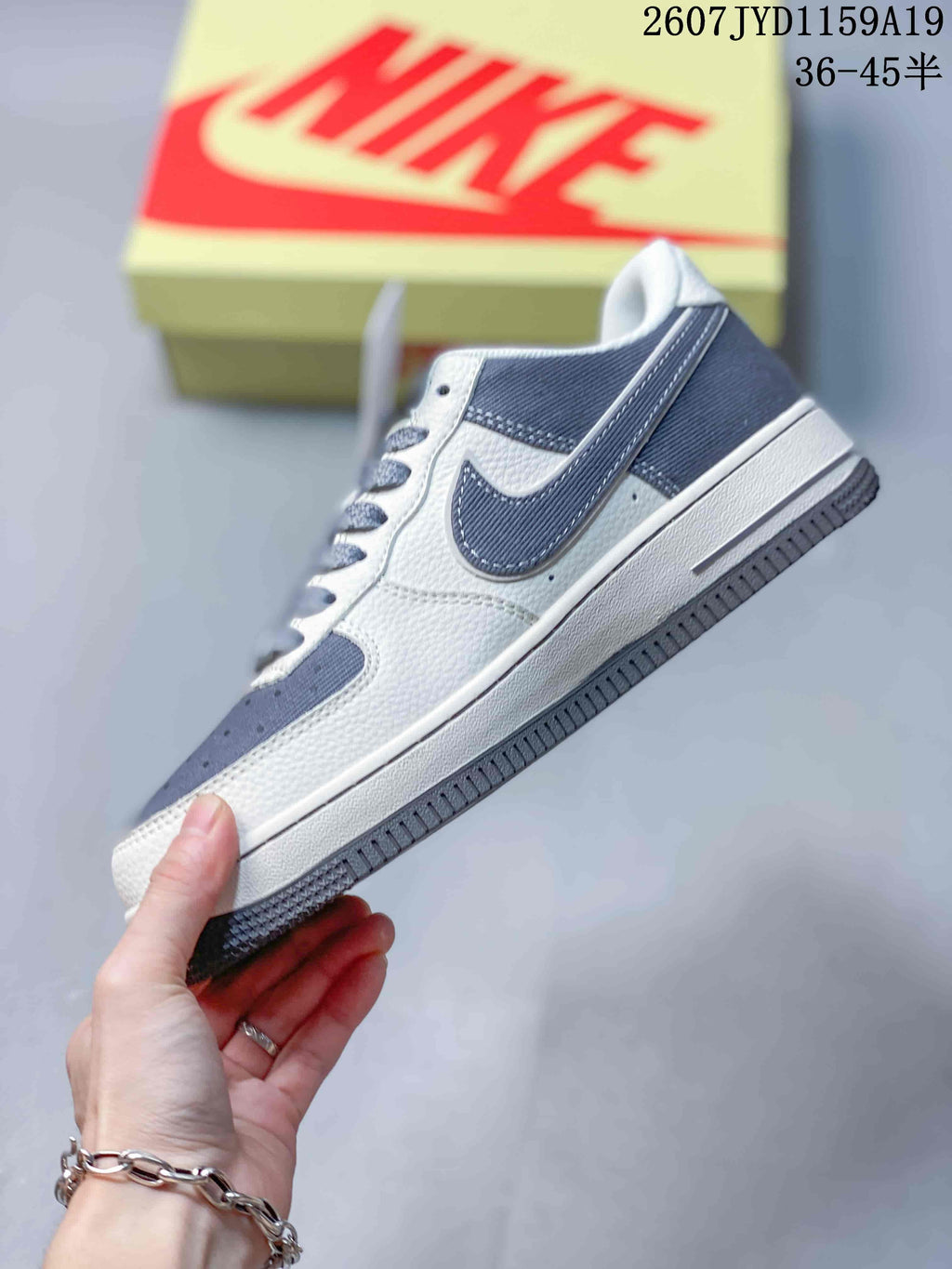 Side view showing the gray Swoosh, white upper panels and layered rubber sole.