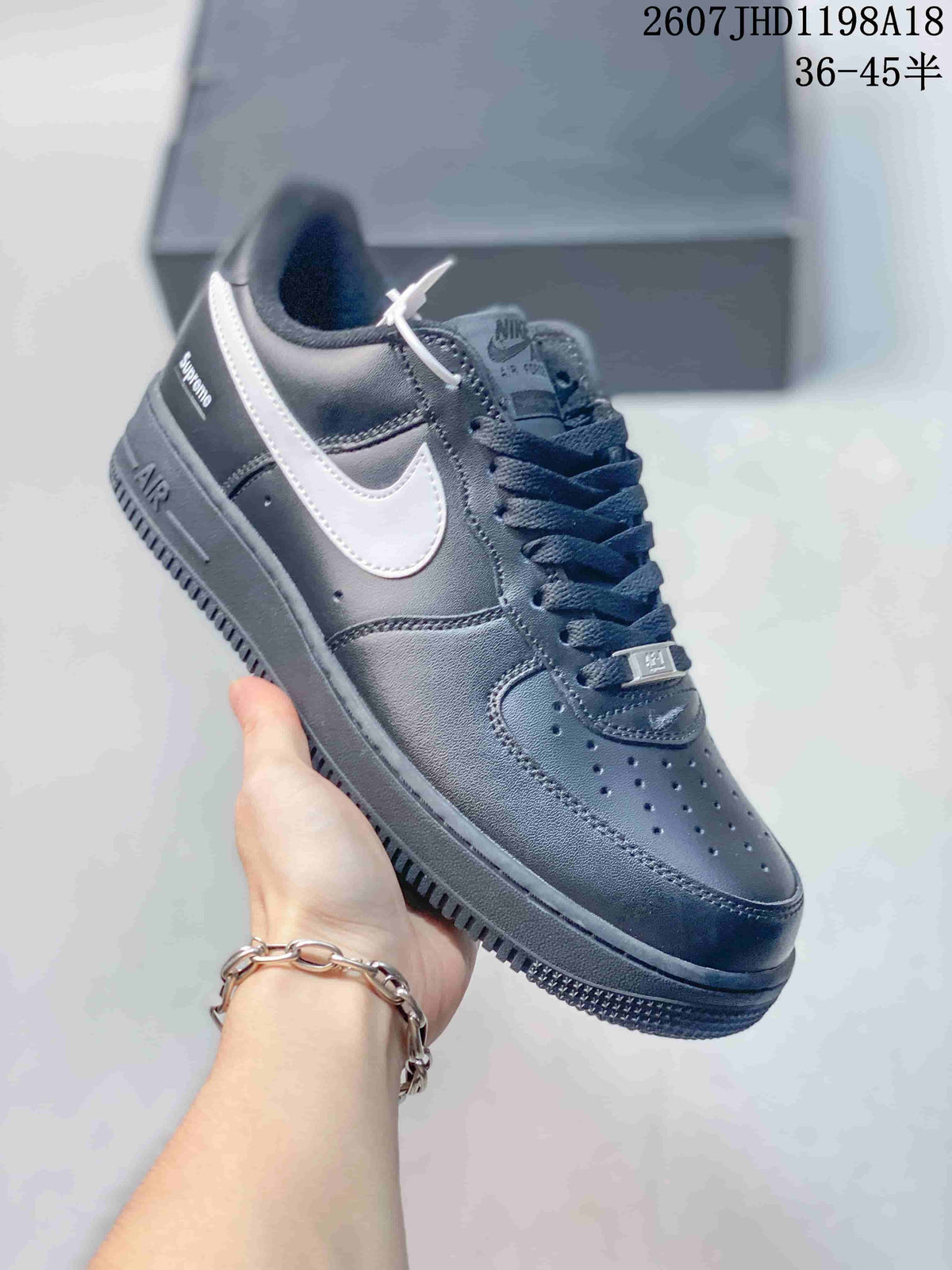 Angled side view of a black and white Nike Air Force 1 '07 Low sneaker showing the white Swoosh, heel detail, padded collar, and rubber outsole; image text shows style code 2607JHD1198A18 and sizes 36–45.5.
