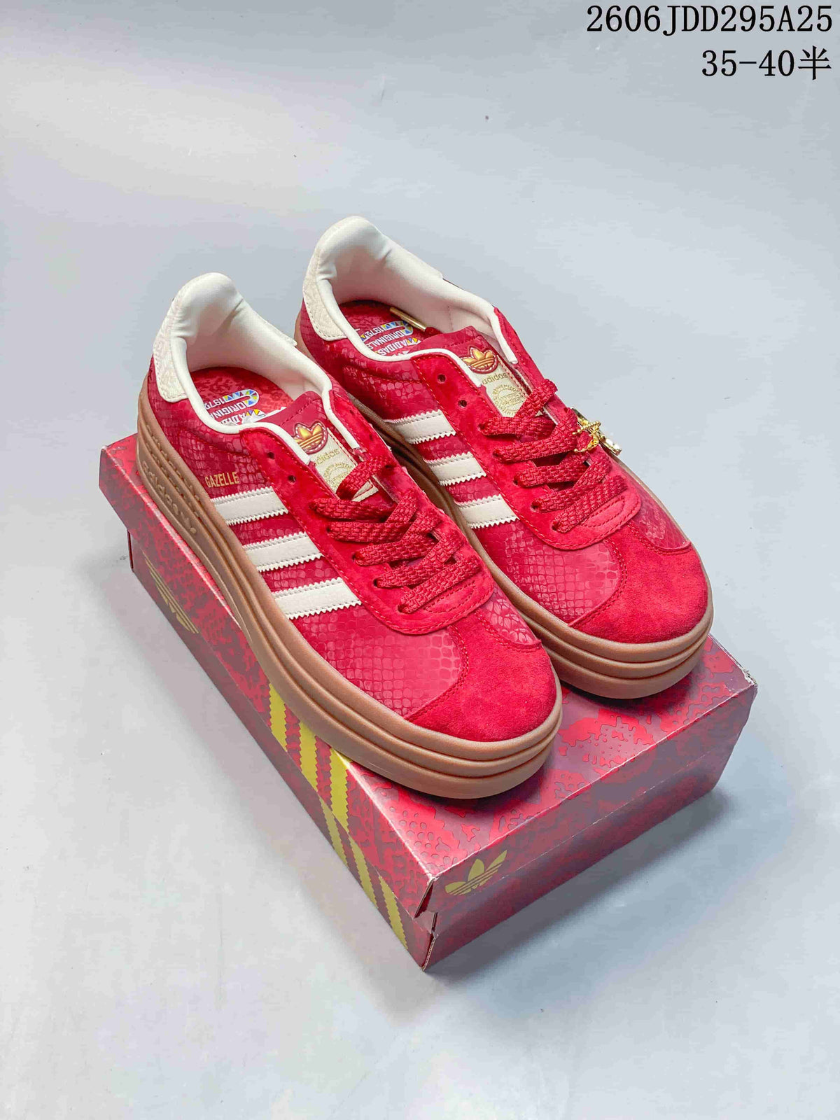Pair of red Adidas Gazelle platform sneakers with white stripes and gum-colored soles, shown on a patterned red box.