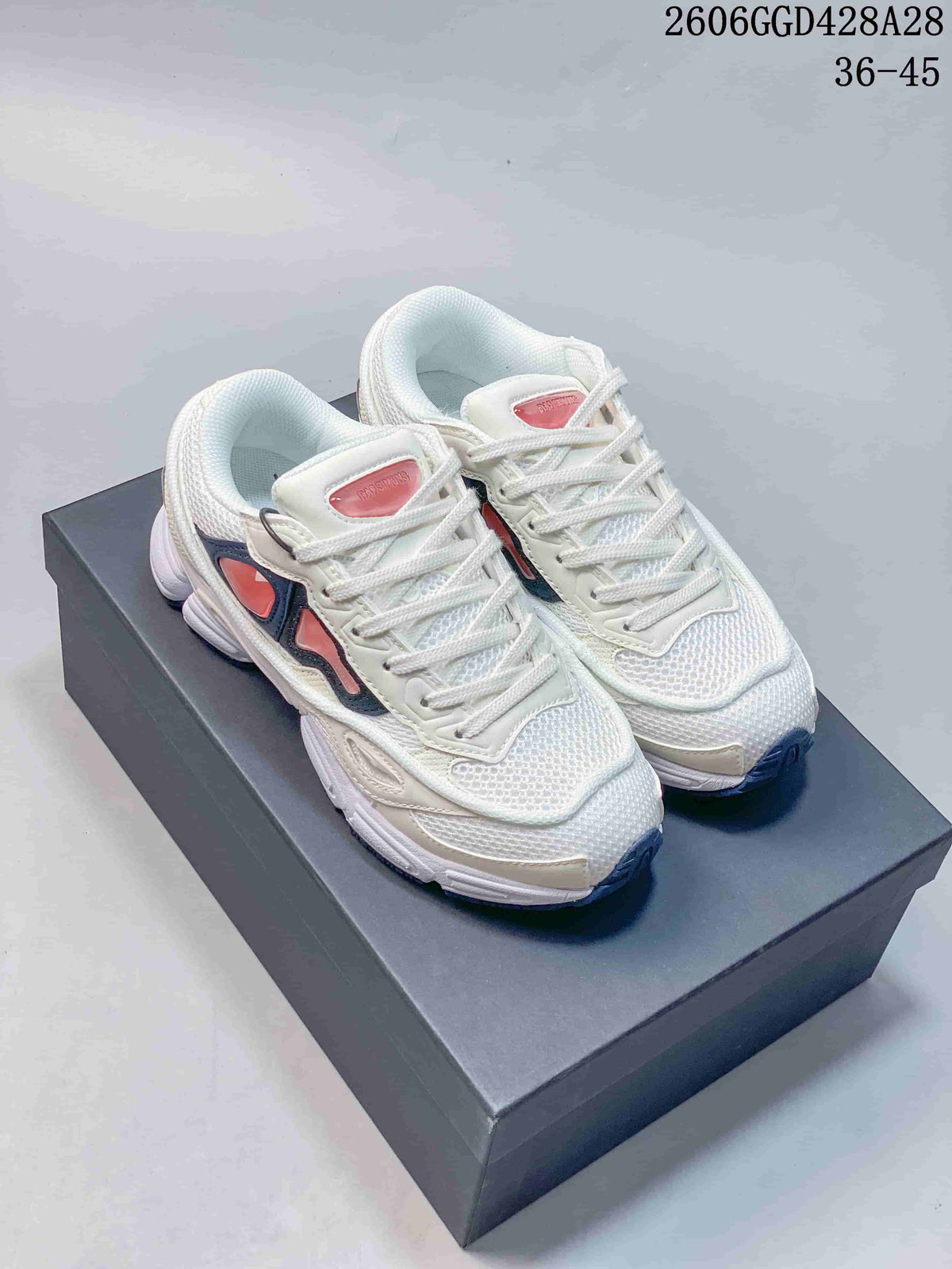 Pair of white Raf Simons Cylon-21 low-top sneakers with navy and coral-pink accents on a box