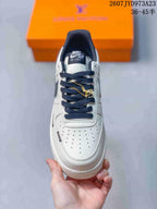 Top view showing the perforated white toe box, navy laces, tongue label, and gold-tone lace accessory.