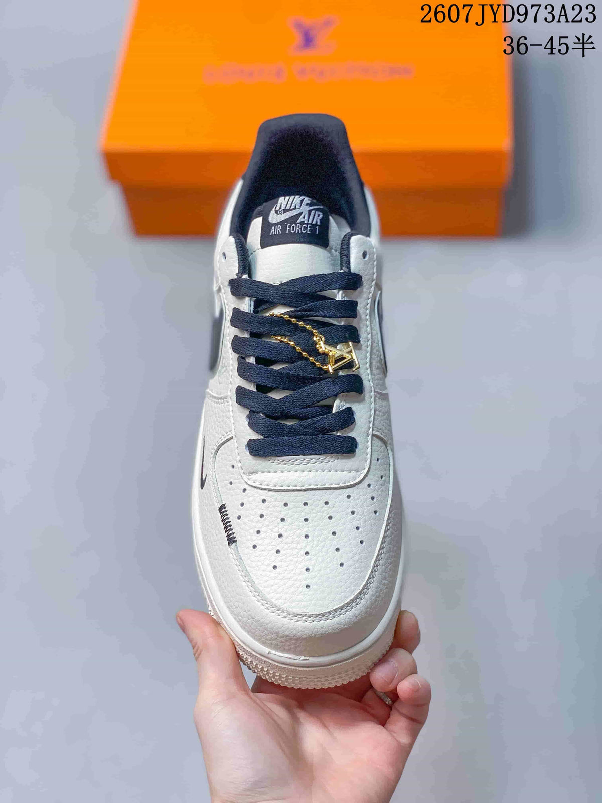 Top view showing the perforated white toe box, navy laces, tongue label, and gold-tone lace accessory.