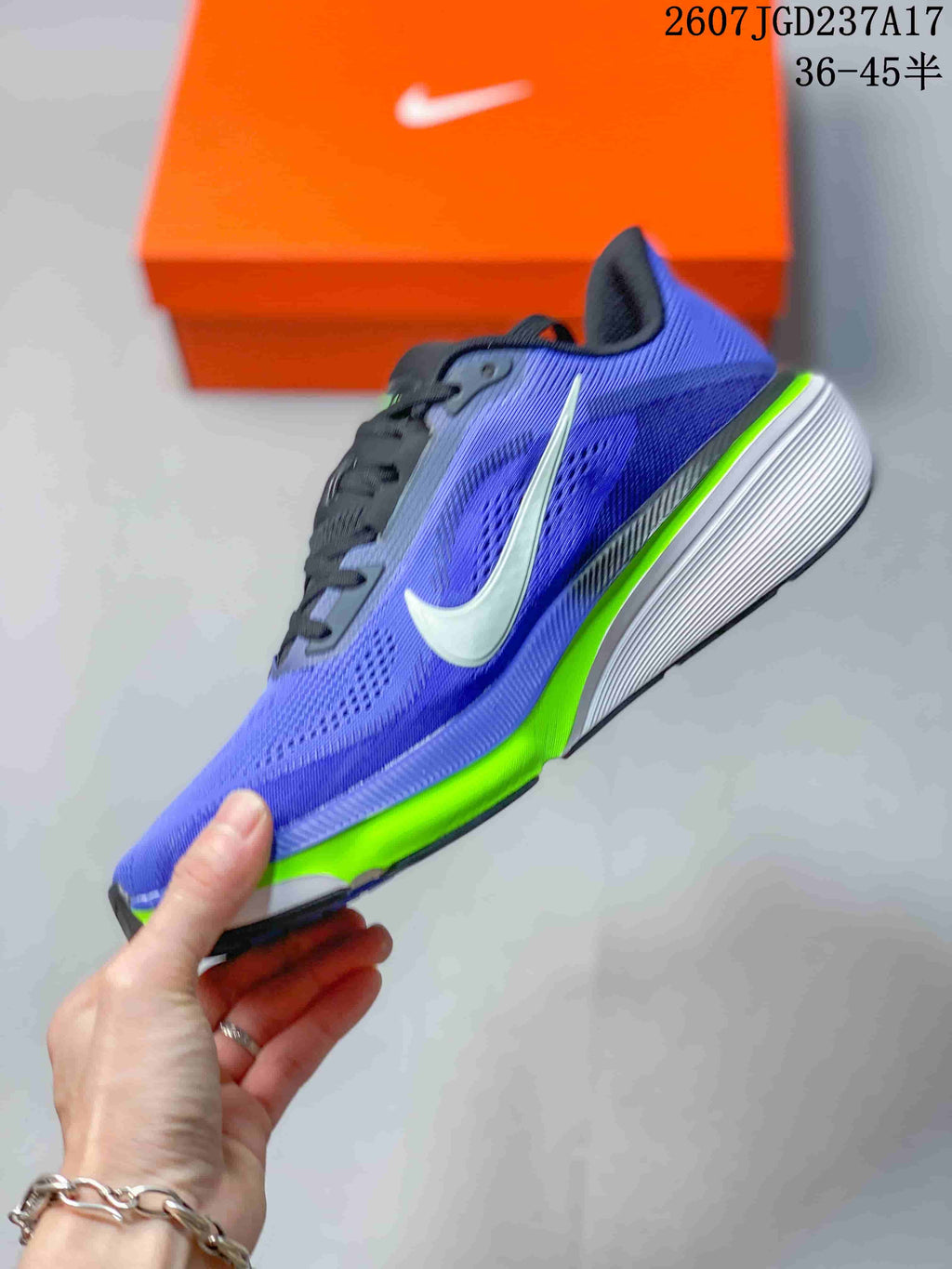 Side view of a purple and blue Nike Air Zoom Pegasus 42 shoe with a white Swoosh, black details, and bright green outsole accent.