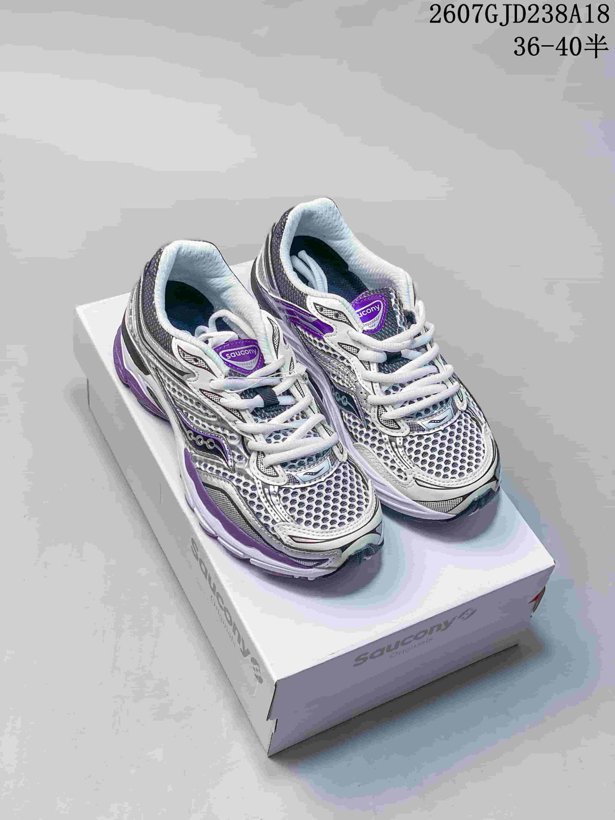 Pair of Saucony Progrid Omni 9 sneakers in white, gray and purple displayed on a shoebox; image text shows code 2607GJD238A18 and size range 36–40 with half sizes.