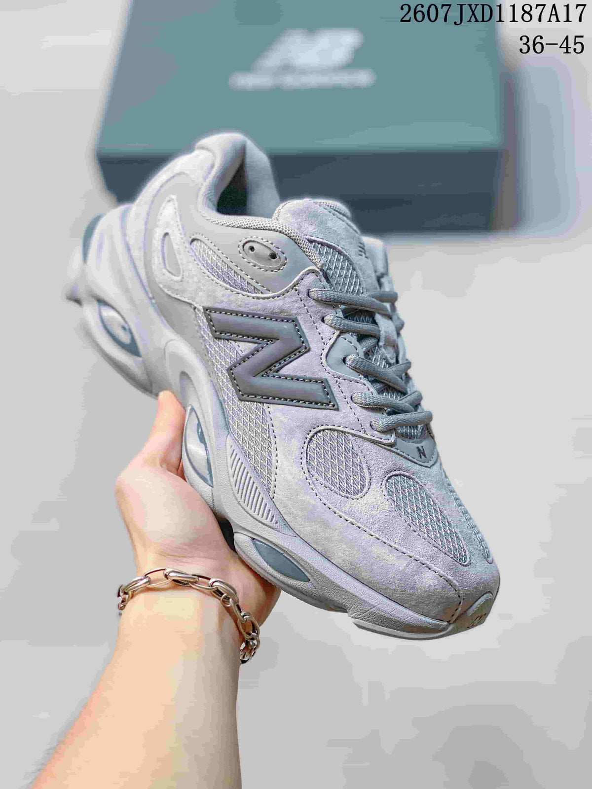 Angled side view of the grey New Balance sneaker showing the layered panels, mesh details, and sculpted outsole.