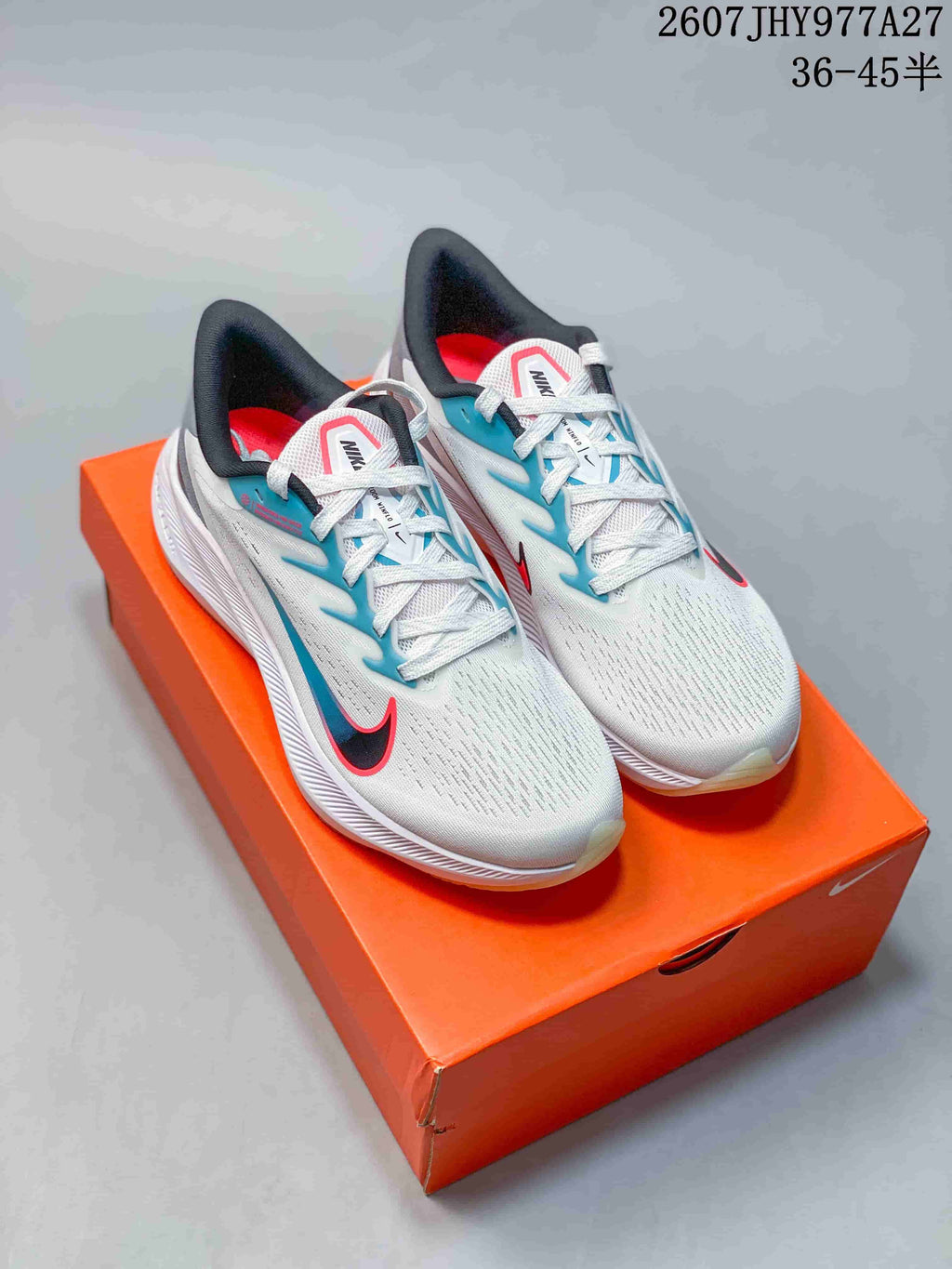 Pair of white Nike Zoom Winflo 7 running shoes with blue and red accents displayed on an orange shoe box.