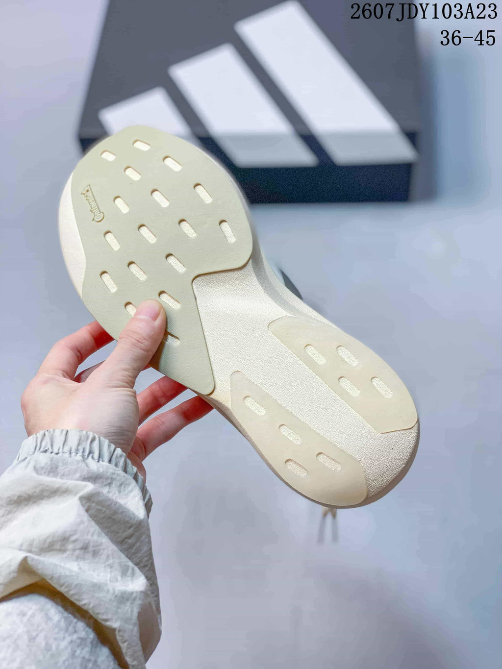 Bottom view of the sneaker showing the cream-colored outsole with elongated traction openings.