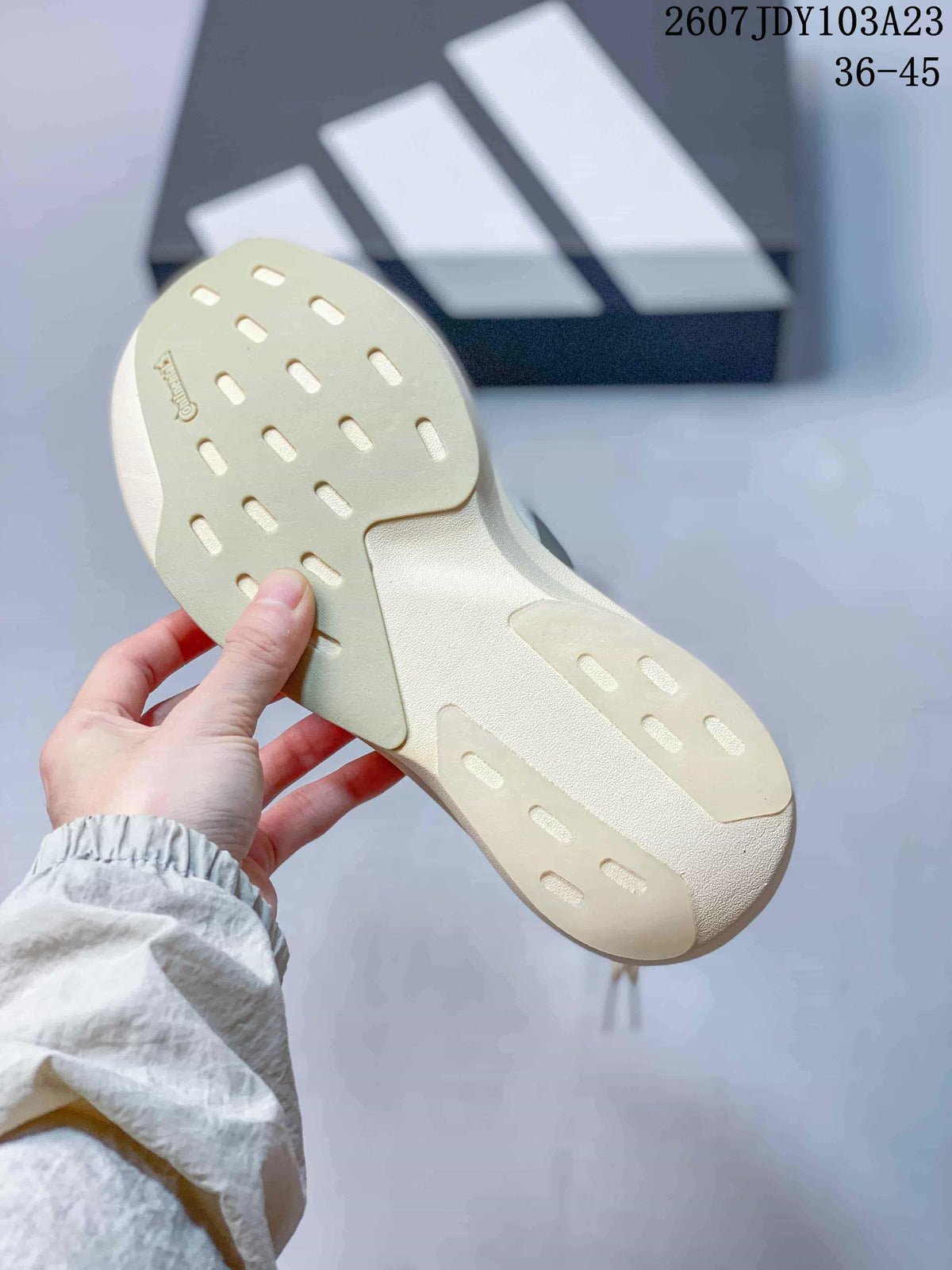 Bottom view of the sneaker showing the cream-colored outsole with elongated traction openings.