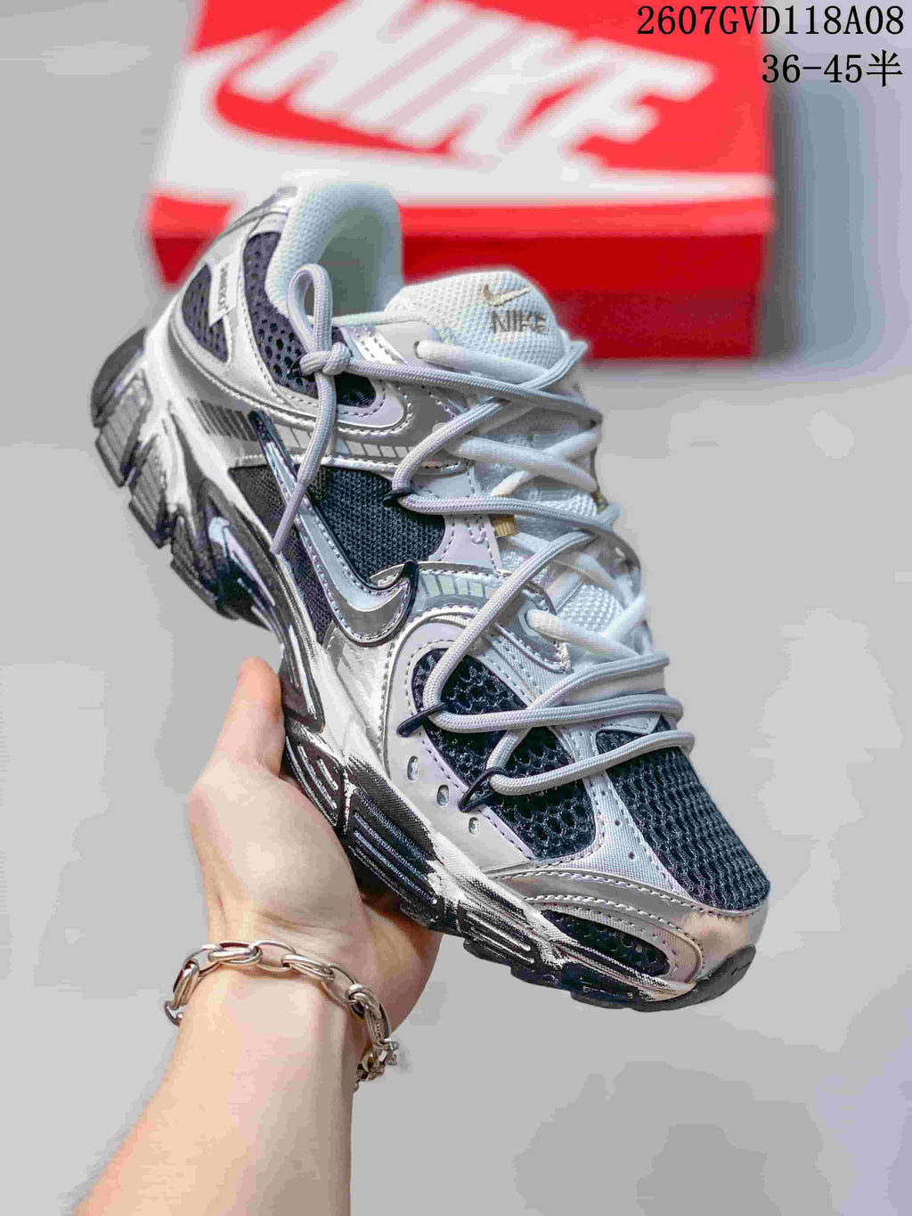 Angled side view of a Nike V5 RNR sneaker showing the white, silver and black layered upper and rugged sole.