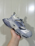 Angled view of an all-grey chunky sneaker with suede-look overlays, mesh panels, dark accents, and a segmented outsole.