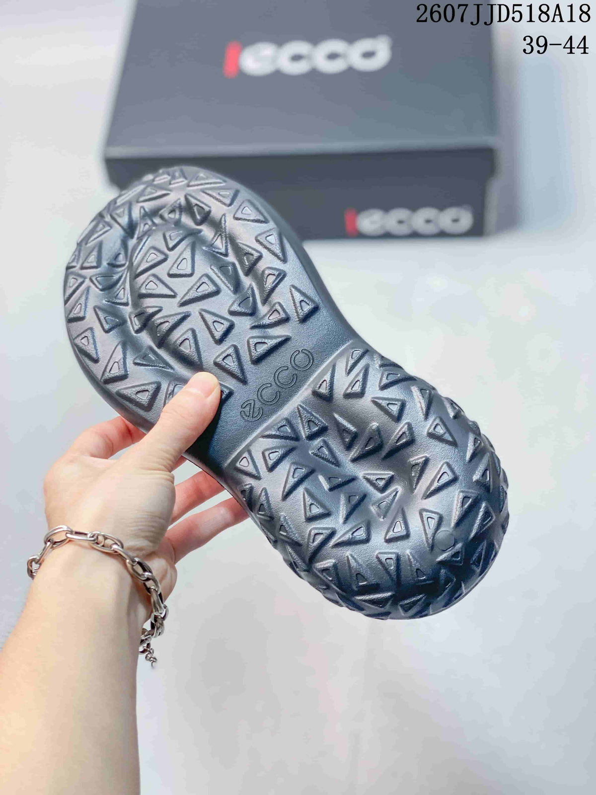 Underside of a black sandal showing the repeating geometric tread pattern and ECCO branding.