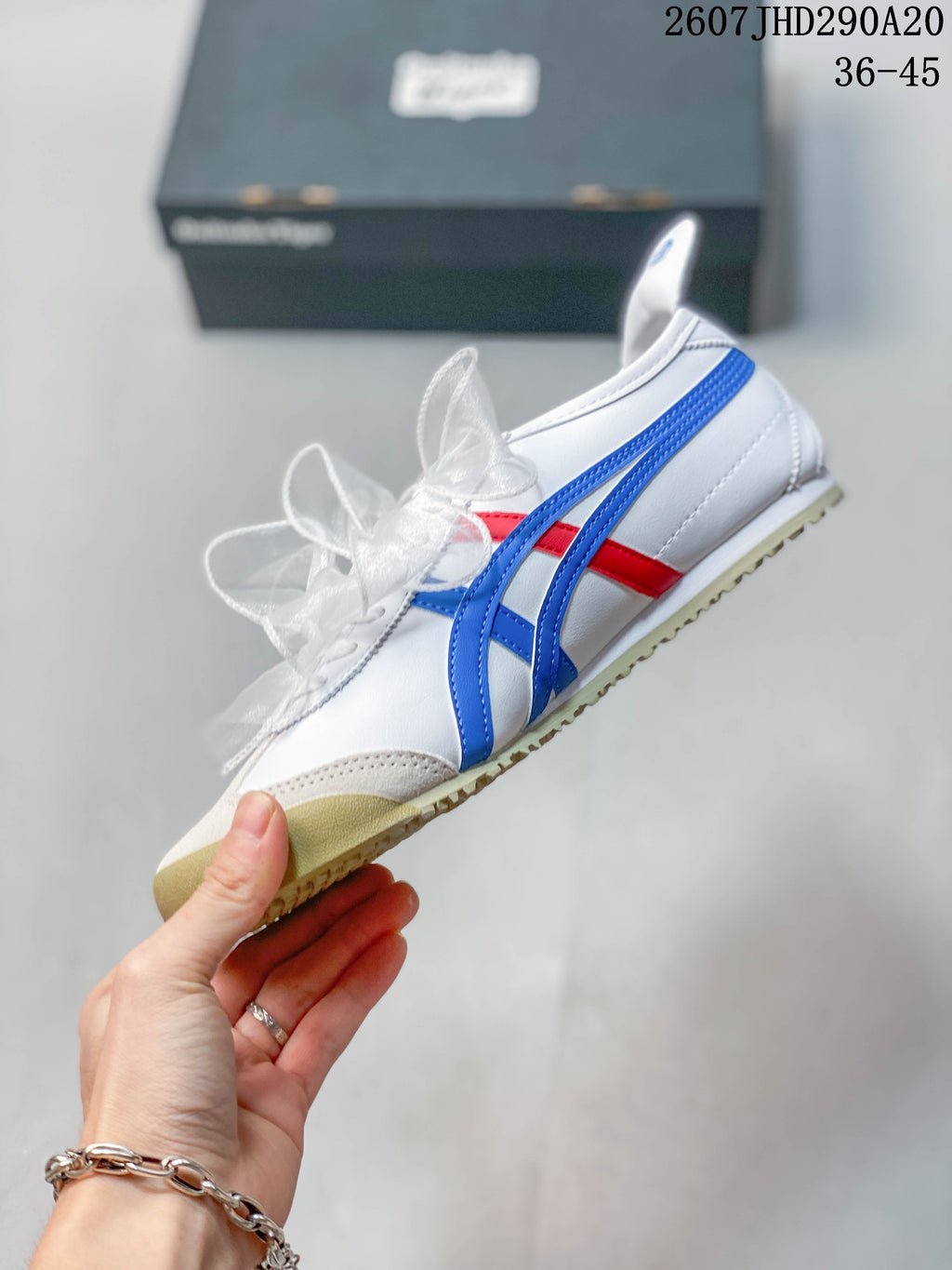 Side profile showing the white upper, blue and red stripes, ribbon-style laces, and low-top shape.