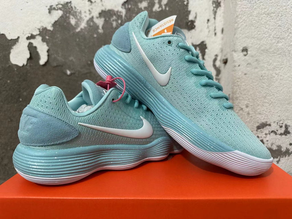 Pair of mint green and white Nike sneakers shown at an angle with pink tag accents