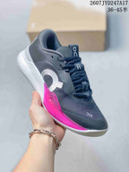 Angled side view of the sneaker showing the dark gray upper, pink side structure, and white midsole.