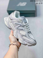 Angled side view of the gray New Balance 9060 sneaker showing the New Balance logo, mesh sections, and sculpted sole.