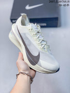 Angled side view of the white and light cream Nike Vaporfly shoe showing the dark Swoosh and layered midsole.