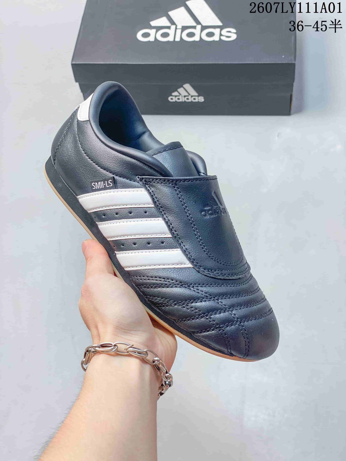 Dark Adidas Taekwondo low-top slip-on sneaker with white stripes and a gum-colored outsole.