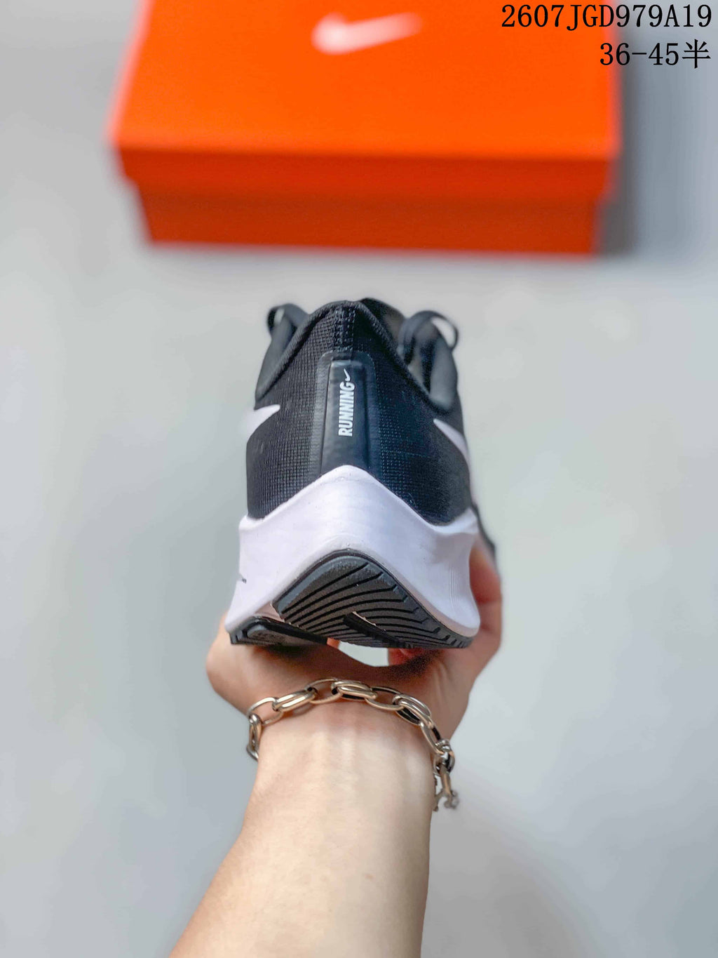 Rear view of the dark sneaker showing the white heel midsole, black outsole, and vertical running detail on the heel.