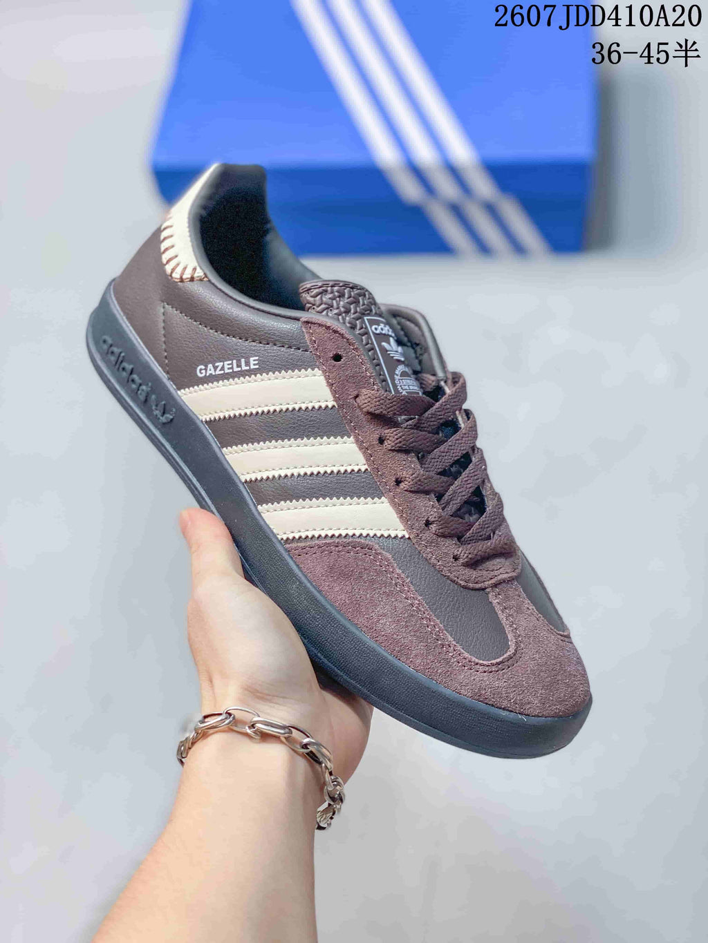 Angled side view showing the visible Gazelle lettering, cream stripes, brown upper, and dark outsole.