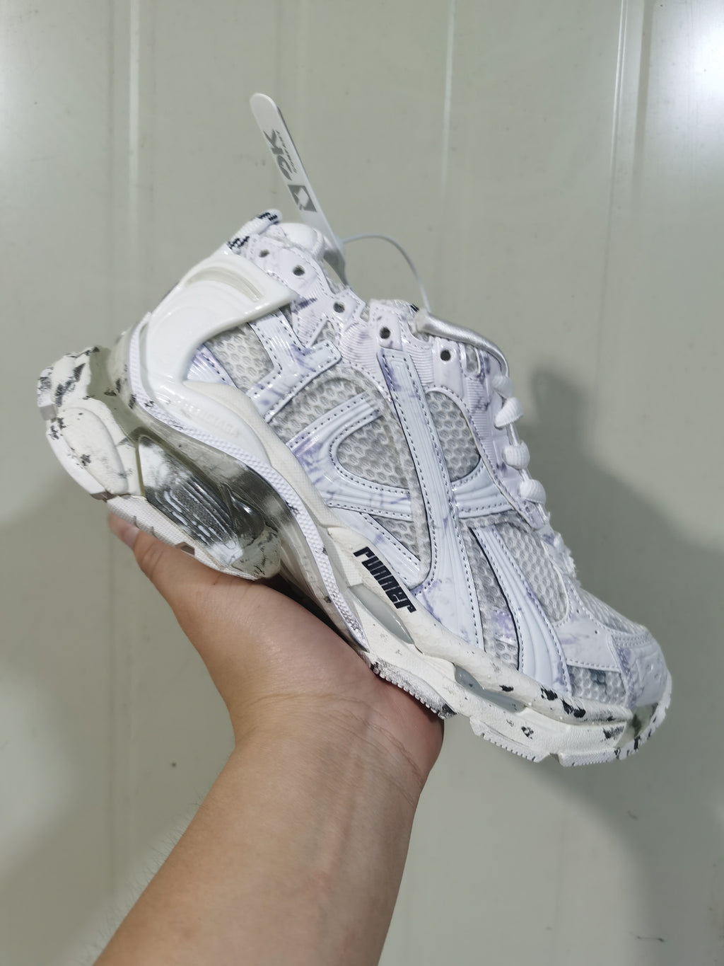 Close-up angled view of white Nike Runner sneakers showing layered panels, mesh sections, laces, and a sculpted sole.
