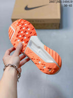 Underside of the shoe showing the bright orange textured outsole with circular openings and traction lugs.