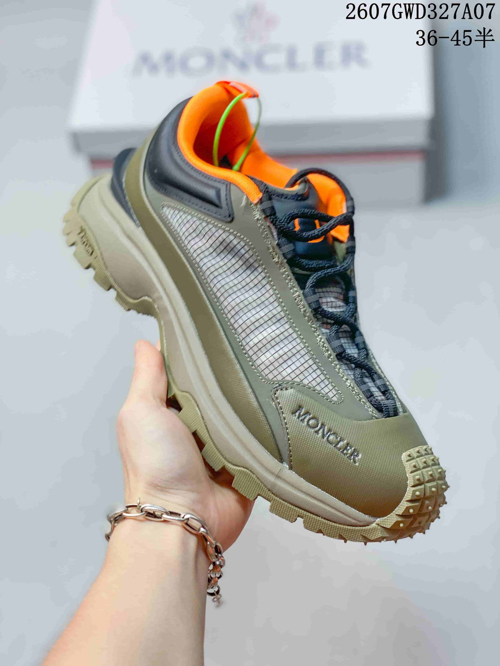 Angled side view of the olive sneaker with orange collar details, black trim, mesh-style paneling and rugged outsole.