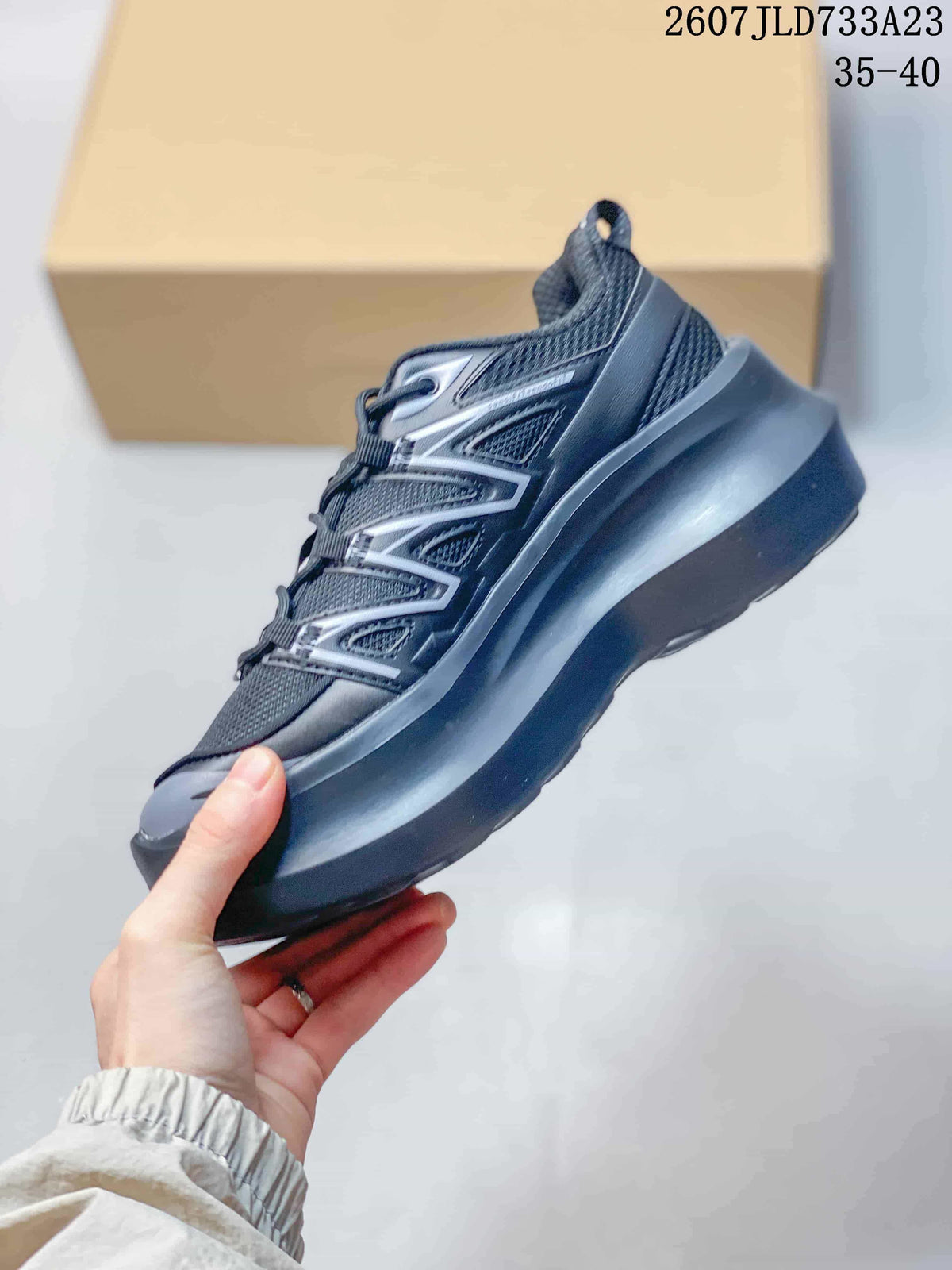 Side profile of the black and gray low-top sneaker showing layered panels and a raised chunky sole.