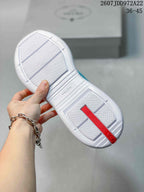 Underside of the sneaker showing a white textured outsole, red heel detail, and Prada branding.