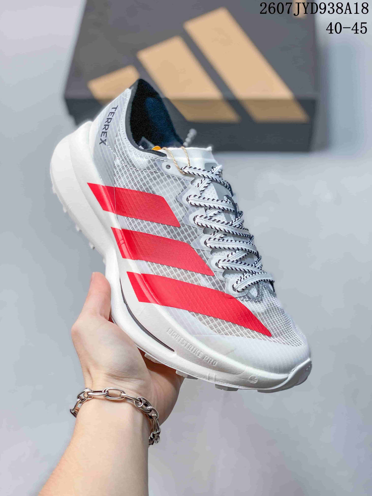 Side view of the shoe showing the white textile upper, red stripes, white midsole, heel branding, and outsole.
