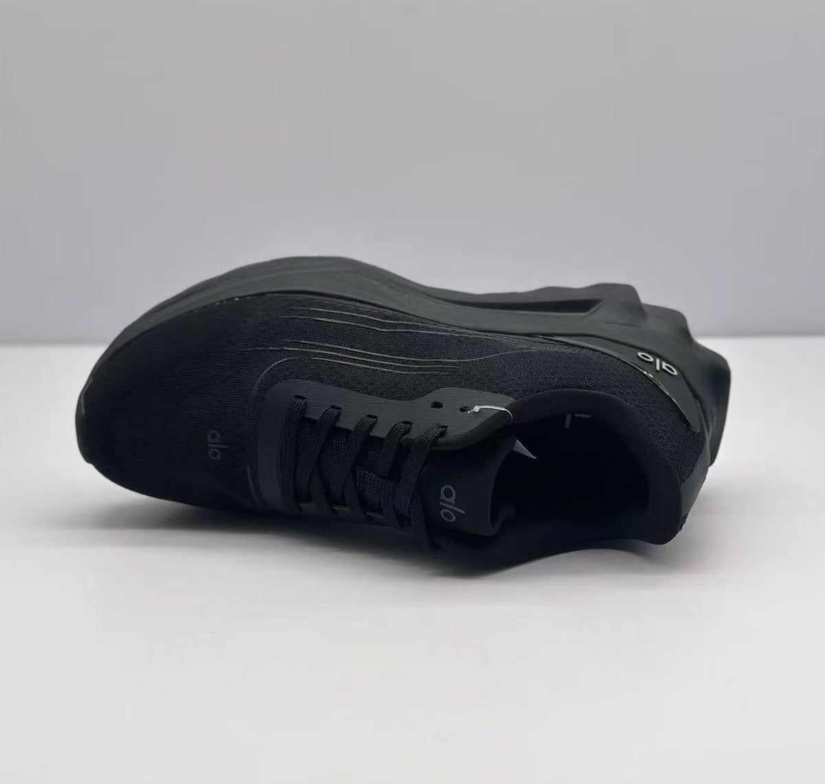 Top view of one black Alo sneaker highlighting the lace panel, textured upper, and tonal branding.