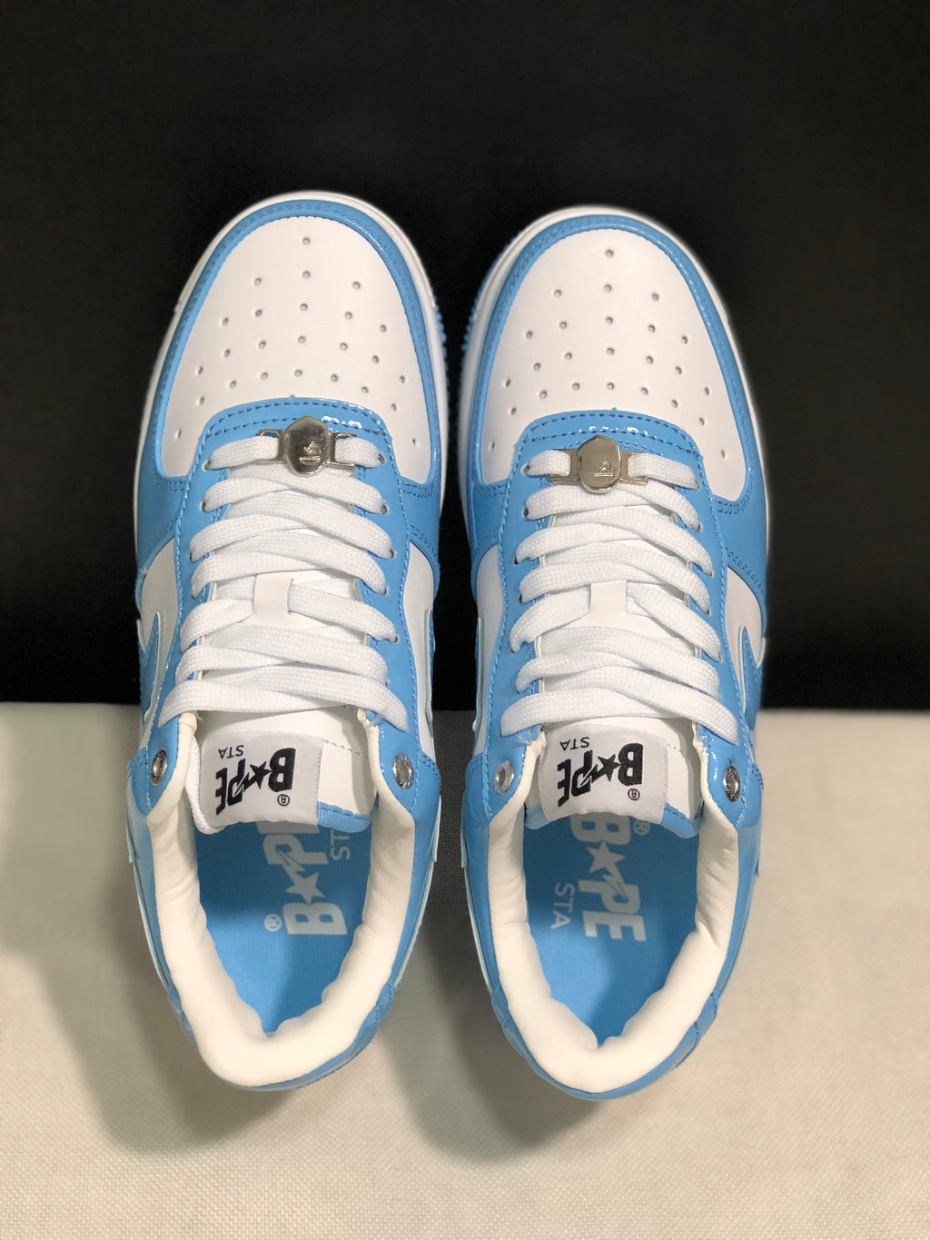 Top-down view showing perforated white toe panels, white laces, metal lace accessories, and branded insoles.