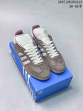Pair of gray and white adidas Samba sneakers displayed on a blue shoebox.