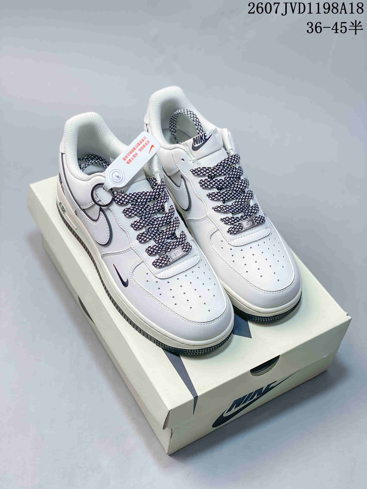 Pair of white Nike low-top sneakers with dark contrasting swooshes, patterned laces, and a matching shoebox.